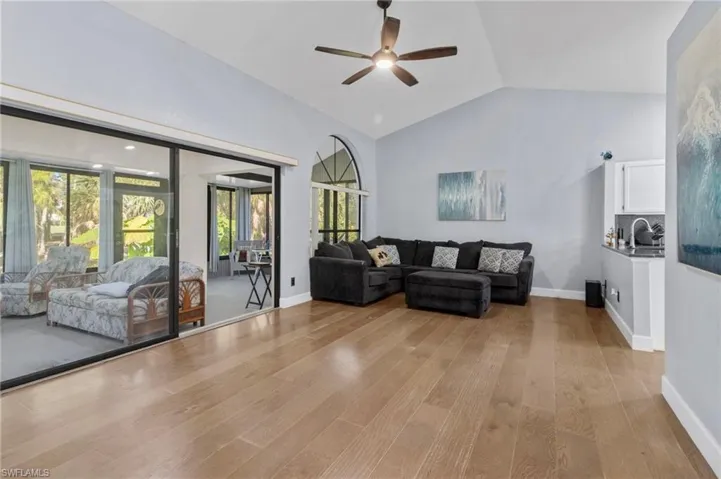 Living room featuring lofted ceiling, sink, light wood-type flooring, and ceiling fan