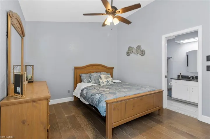 Guest Bedroom with ensuite bath, ceiling fan, hardwood / wood-style flooring, and lofted ceiling