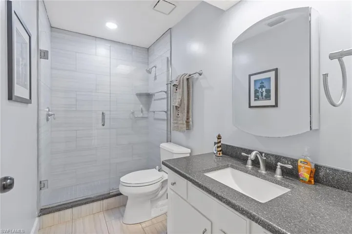Guest ensuite bathroom with vanity, a shower with shower door, toilet, and tile patterned floors