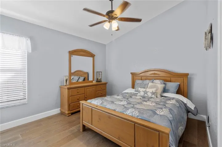 Guest Bedroom featuring light hardwood / wood-style floors, vaulted ceiling, and ceiling fan
