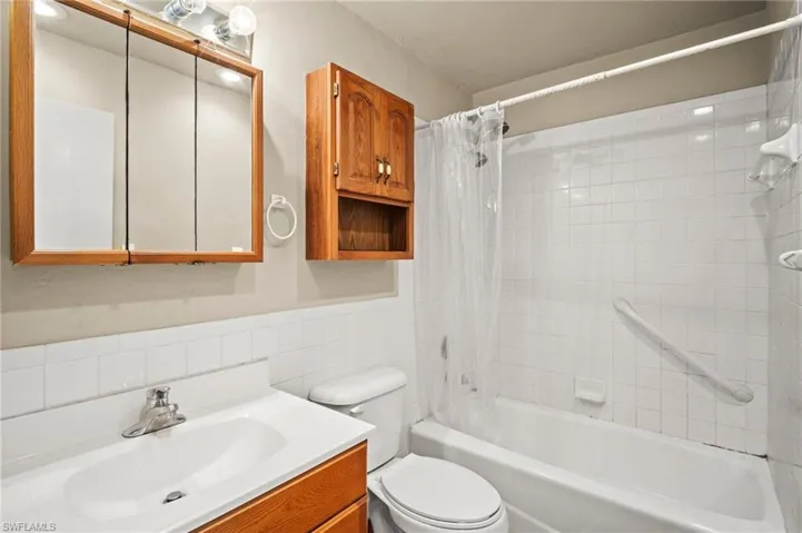 Bathroom featuring toilet, vanity, tile walls, and shower / tub combo