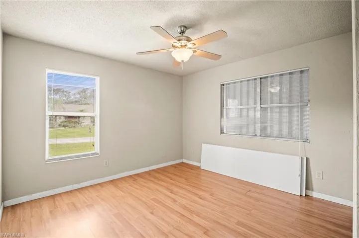 Empty room with baseboards, a textured ceiling, ceiling fan, and light wood finished floors