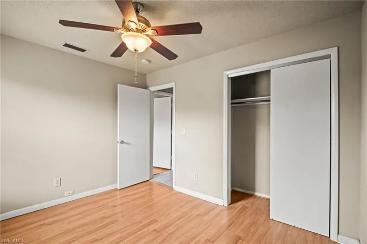 Unfurnished bedroom with wood finished floors, a textured ceiling, a closet, and visible vents