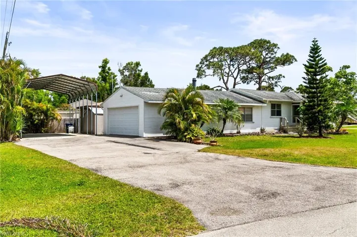 Single story home featuring driveway, a carport, a front yard, and a garage
