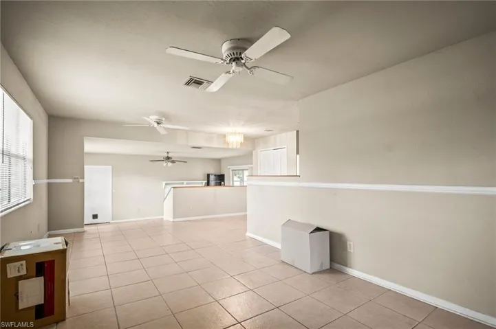 Empty room with light tile patterned floors, visible vents, baseboards, and ceiling fan