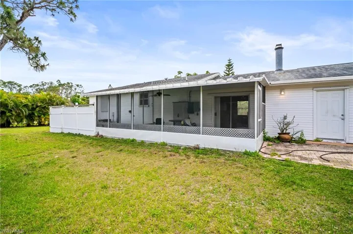 Back of house featuring a lawn, a sunroom, a chimney, and fence