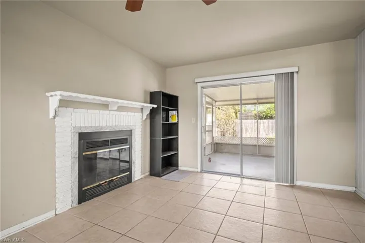 Unfurnished living room with a ceiling fan, light tile patterned flooring, baseboards, and a fireplace