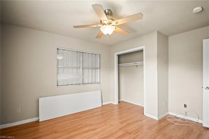 Unfurnished bedroom with baseboards, a closet, light wood-style flooring, and a ceiling fan