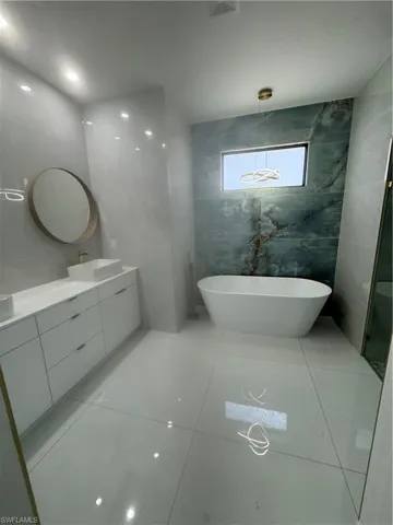 Bathroom featuring tile floors, oversized vanity, a bath, and tile walls