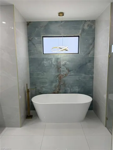 Bathroom featuring tile walls, tile floors, and a bath