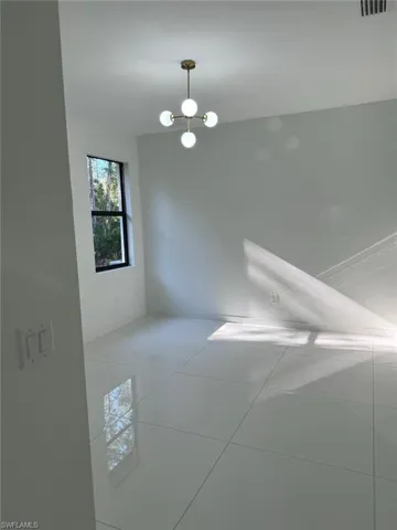 Spare room with light tile flooring and a chandelier