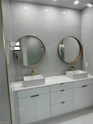 Bathroom featuring tile walls, tile flooring, tasteful backsplash, and double sink vanity