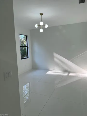 Unfurnished room featuring tile floors and a chandelier