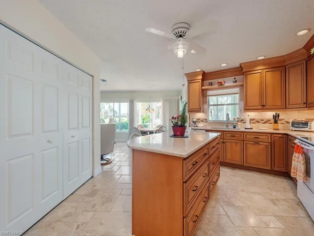 Kitchen featuring brown cabinets, a kitchen island, a ceiling fan, a textured ceiling, and recessed lighting