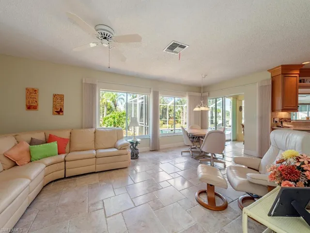 Living area featuring a textured ceiling, stone tile floors, and a ceiling fan