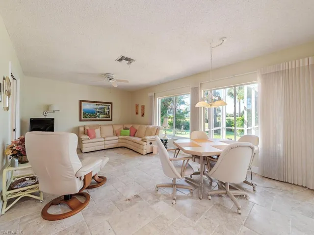 Dining space with a textured ceiling, ceiling fan, and light stone finish floors