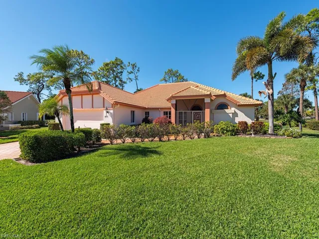 Mediterranean / spanish house with stucco siding, a tiled roof, and a front lawn