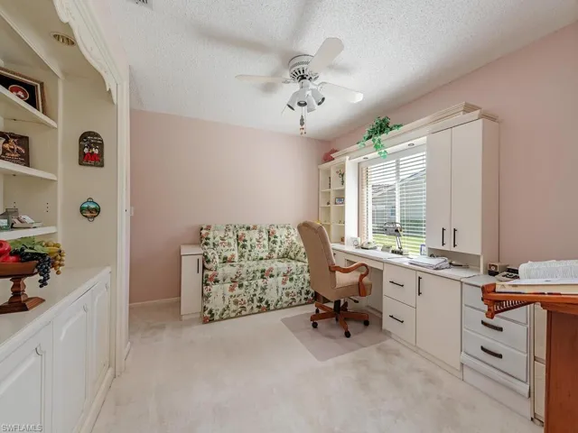 Office space with a textured ceiling, light colored carpet, a ceiling fan, and built in features