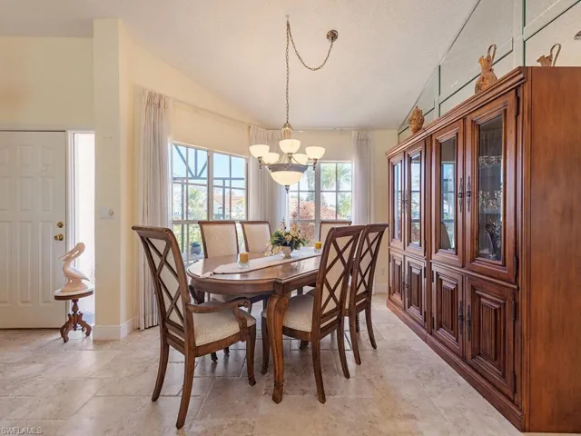 Dining space with vaulted ceiling and light stone finish flooring