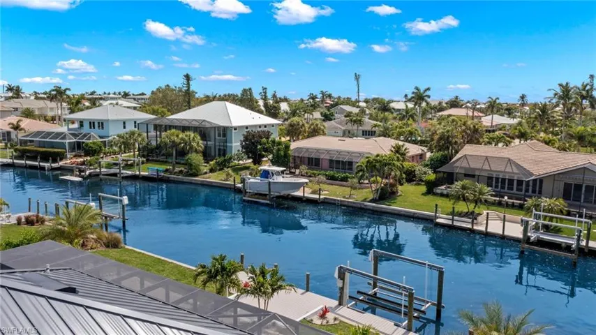 View of pool featuring a water view, glass enclosure, a dock, and a lawn