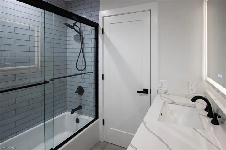Bathroom with enclosed tub / shower combo and sink