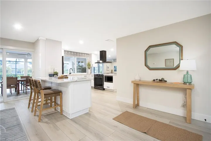 Kitchen with white cabinetry, a kitchen breakfast bar, exhaust hood, light hardwood / wood-style floors, and kitchen peninsula