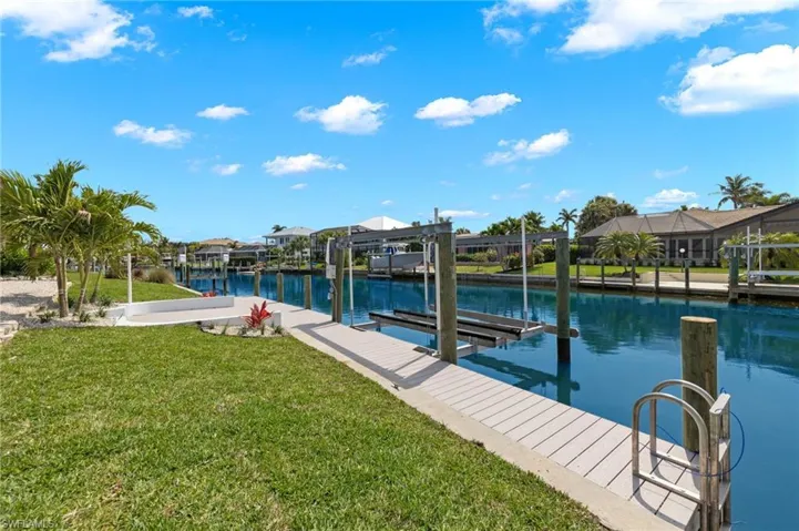View of dock featuring a lanai, a yard, and a water view
