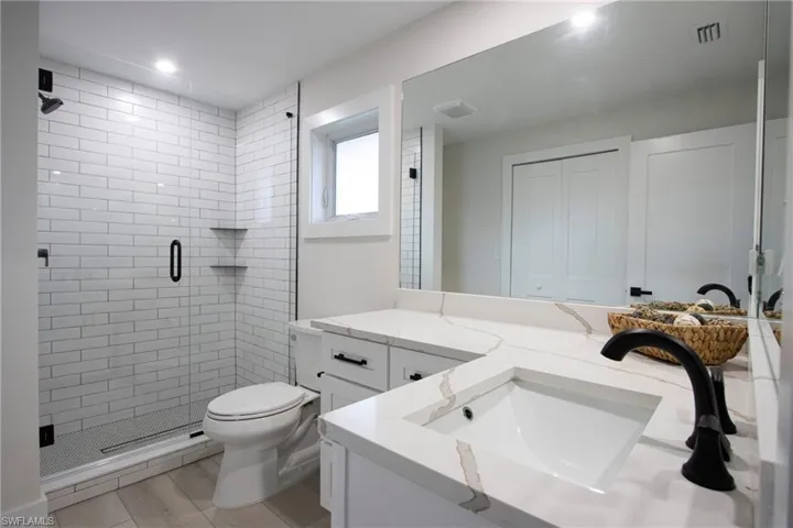 Bathroom with vanity, toilet, an enclosed shower, and wood-type flooring