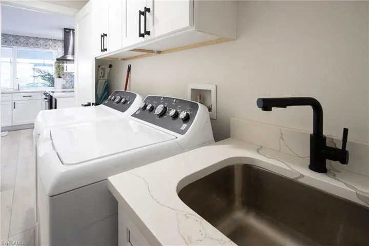 Laundry room featuring cabinets, sink, independent washer and dryer, and light hardwood / wood-style floors