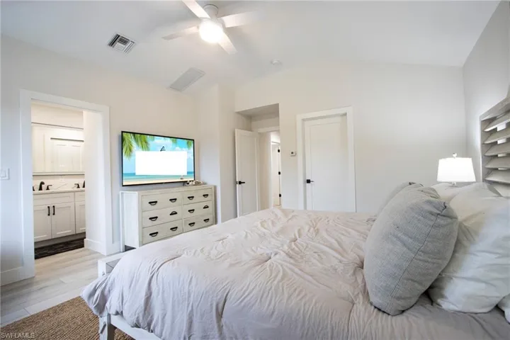 Bedroom with lofted ceiling, sink, ceiling fan, connected bathroom, and light wood-type flooring