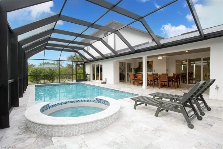 View of pool featuring an in ground hot tub, a patio area, and glass enclosure