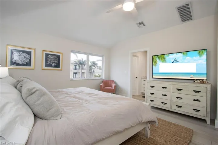 Bedroom with ceiling fan, lofted ceiling, and light wood-type flooring