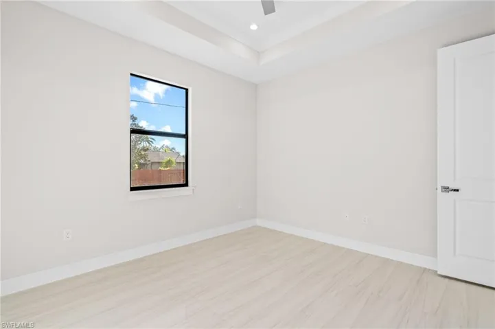 Unfurnished room with a raised ceiling, recessed lighting, and light floors