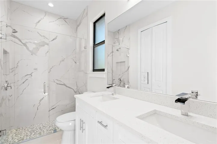 Full bathroom featuring double vanity, a marble finish shower, and a closet