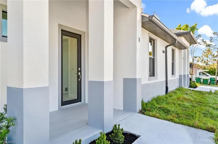 Property entrance with stucco siding and a yard
