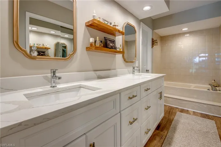 Bathroom featuring tiled shower / bath combo, hardwood / wood-style floors, and dual bowl vanity