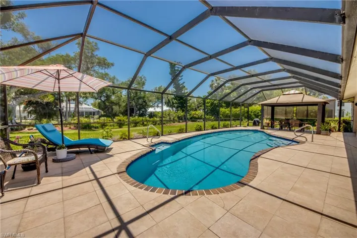 View of pool with a patio area, glass enclosure, and a gazebo