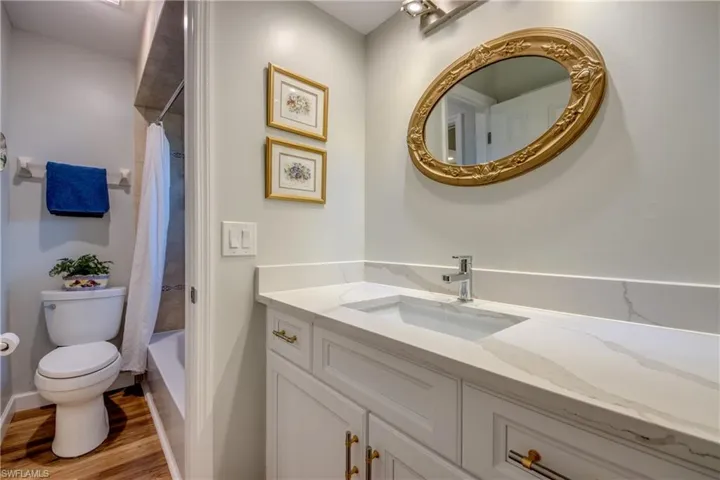 Full bathroom with shower / bath combo with shower curtain, vanity, toilet, and hardwood / wood-style flooring