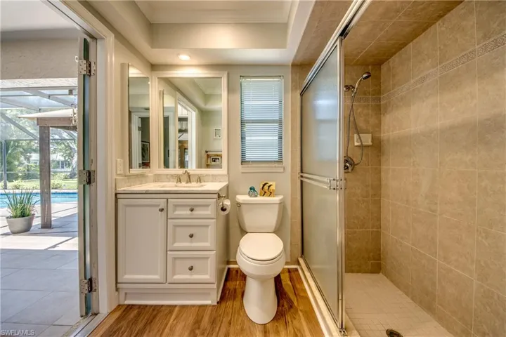 Bathroom featuring an enclosed shower, ornamental molding, hardwood / wood-style flooring, toilet, and large vanity