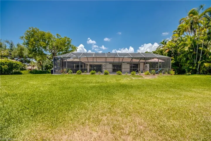Back of house with a lanai and a yard