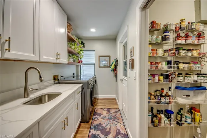 Laundry area featuring independent washer and dryer, light wood-type flooring, washer hookup, sink, and cabinets