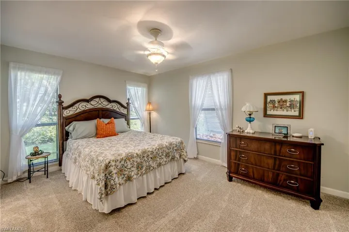 Bedroom featuring ceiling fan, multiple windows, and light colored carpet