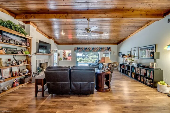 Living room featuring ceiling fan, a fireplace, and hardwood / wood-style flooring