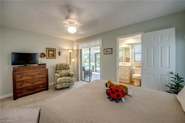 Bedroom with access to outside, ensuite bathroom, ceiling fan, light colored carpet, and sink