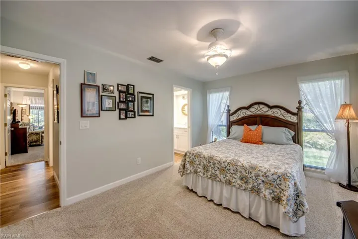 Bedroom with ceiling fan, hardwood / wood-style floors, and connected bathroom