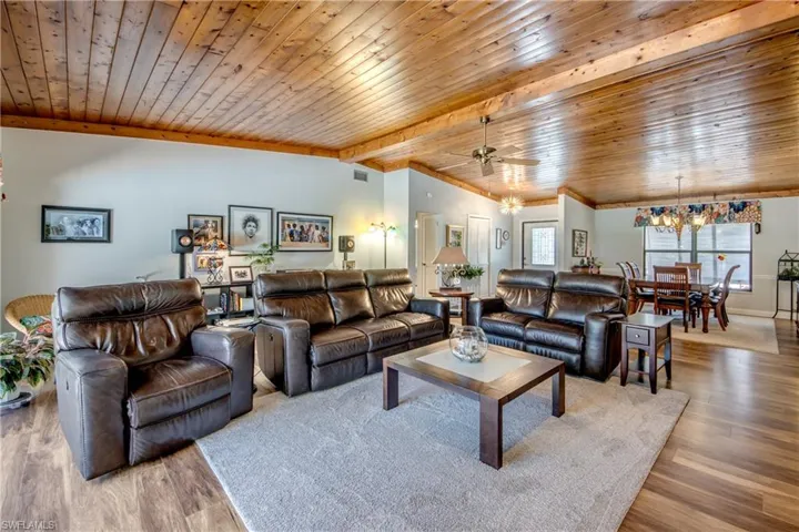 Living room with wood-type flooring, wooden ceiling, and ceiling fan with notable chandelier