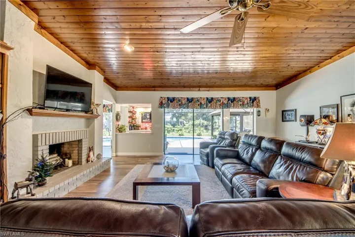 Living room featuring crown molding, a fireplace, wood-type flooring, and ceiling fan