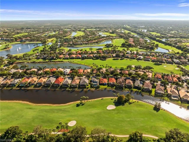 Aerial perspective of suburban area featuring a golf club and a nearby body of water