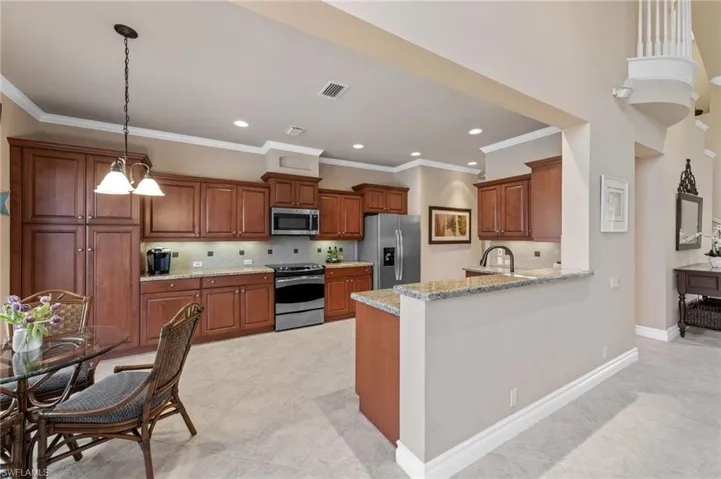 Kitchen featuring decorative backsplash, decorative light fixtures, brown cabinets, appliances with stainless steel finishes, and ornamental molding