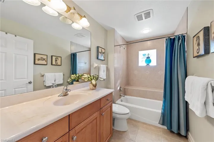 Full bath featuring shower / bath combo with shower curtain, vanity, and light tile patterned floors